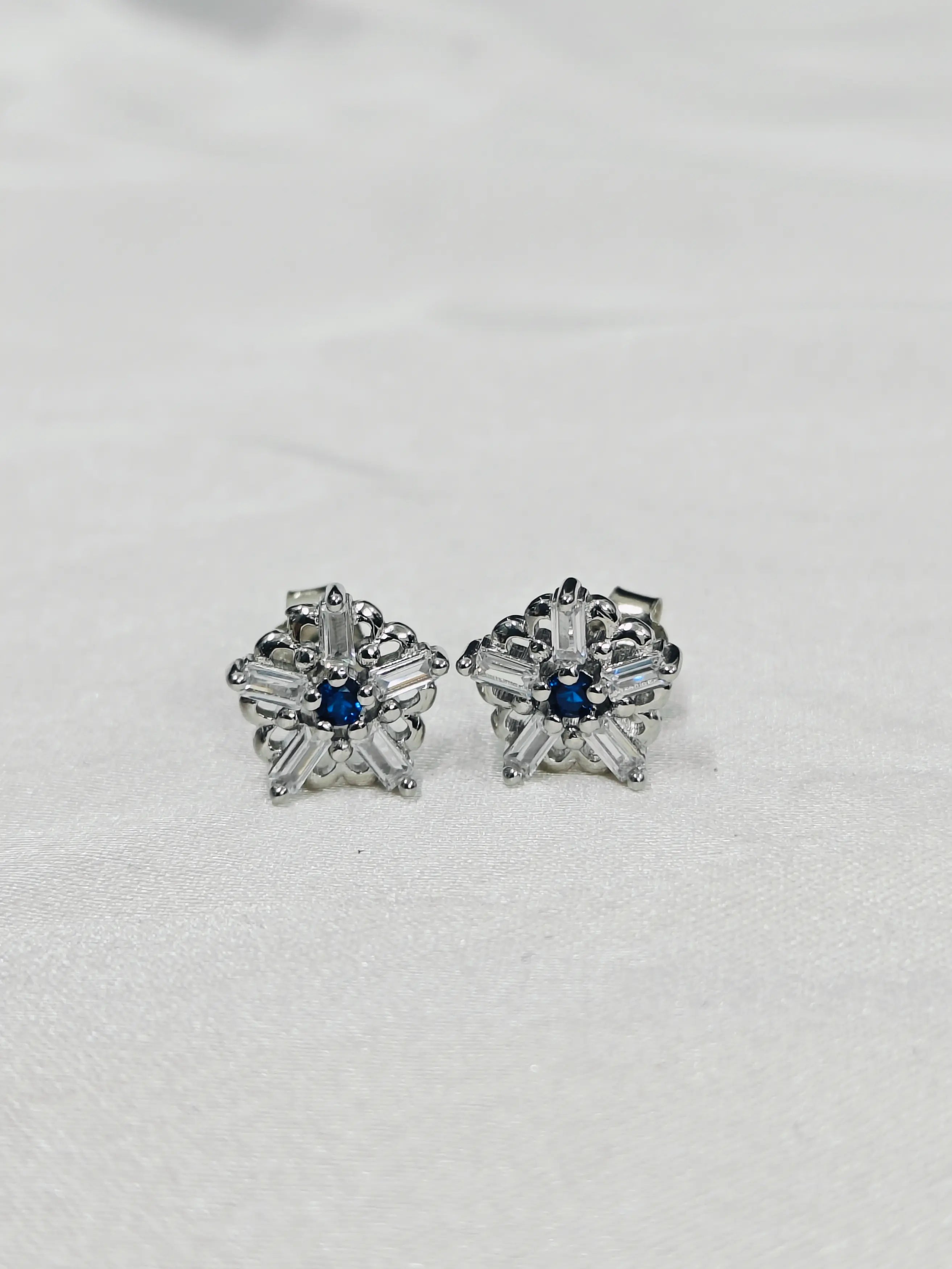 Pair of silver earrings with blue gemstones on a light gray background